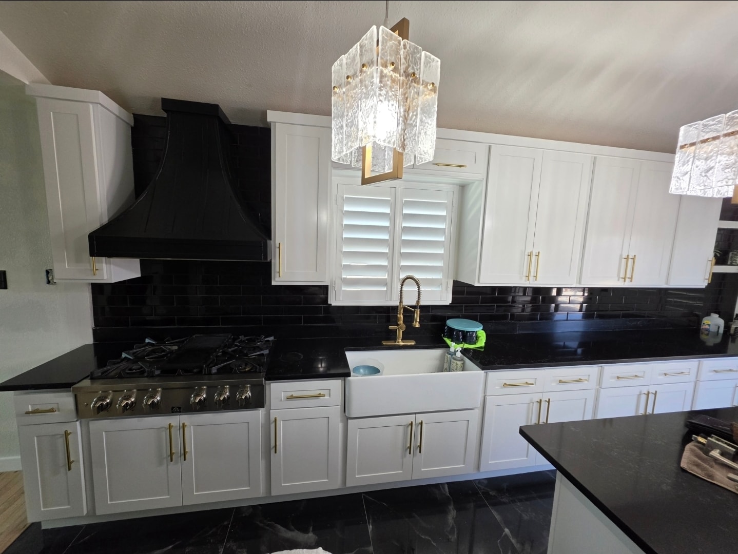 Refinished white kitchen cabinets with black subway tile backsplash and brass hardware