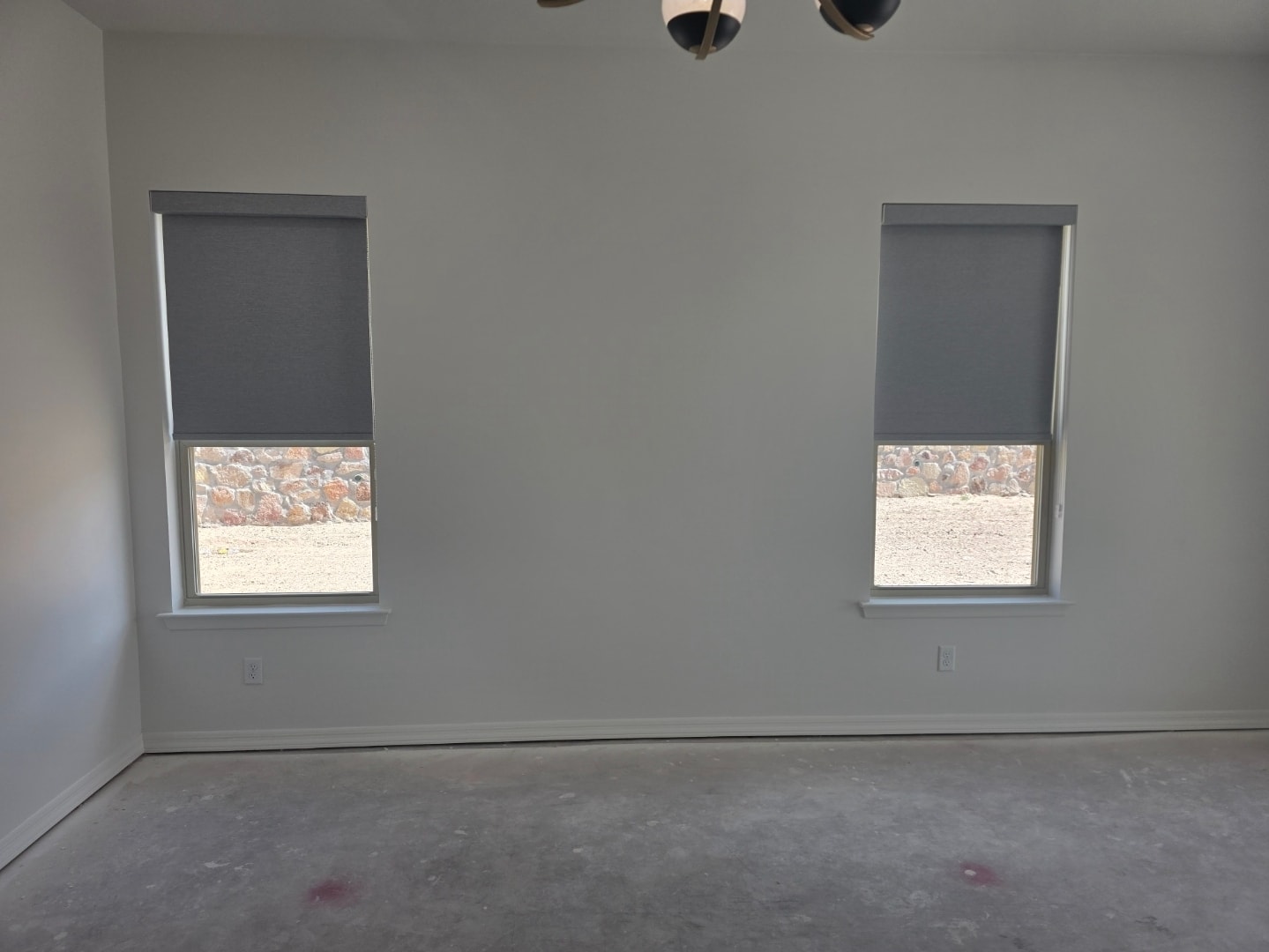 Gray roller shades on two bedroom windows with ceiling fan